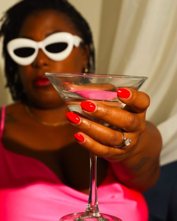 LAUNA in white cat-eye sunglasses holding a martini glass, hot pink top, red nails