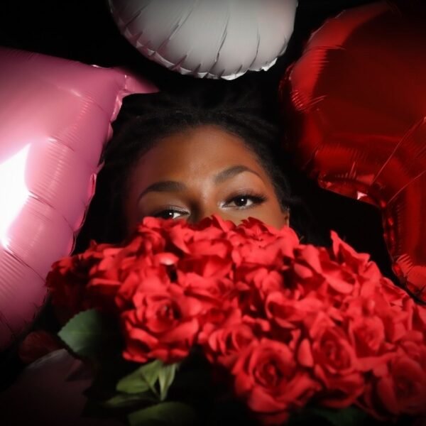 A bouquet of deep red roses against pink and white balloons