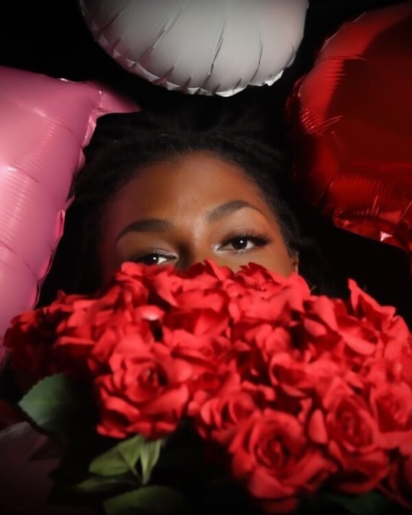 A bouquet of deep red roses against pink and white balloons